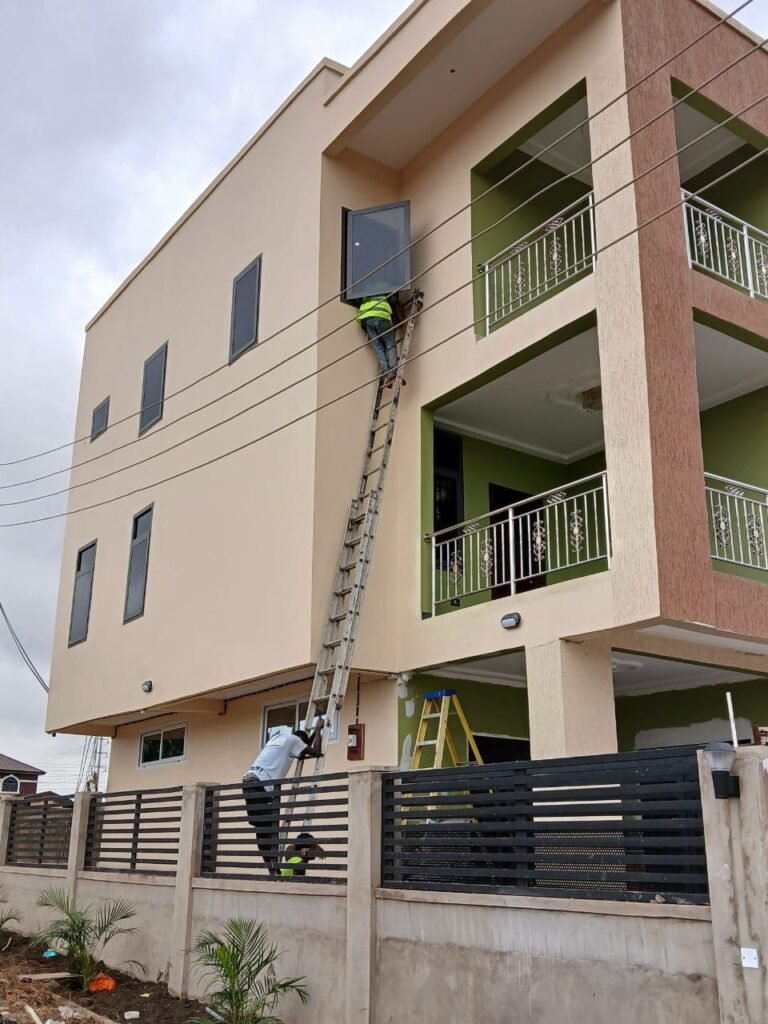Cleaners on ladders washing the windows of a three-storey building